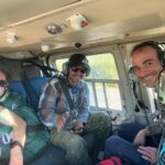Four people smile inside a helicopter