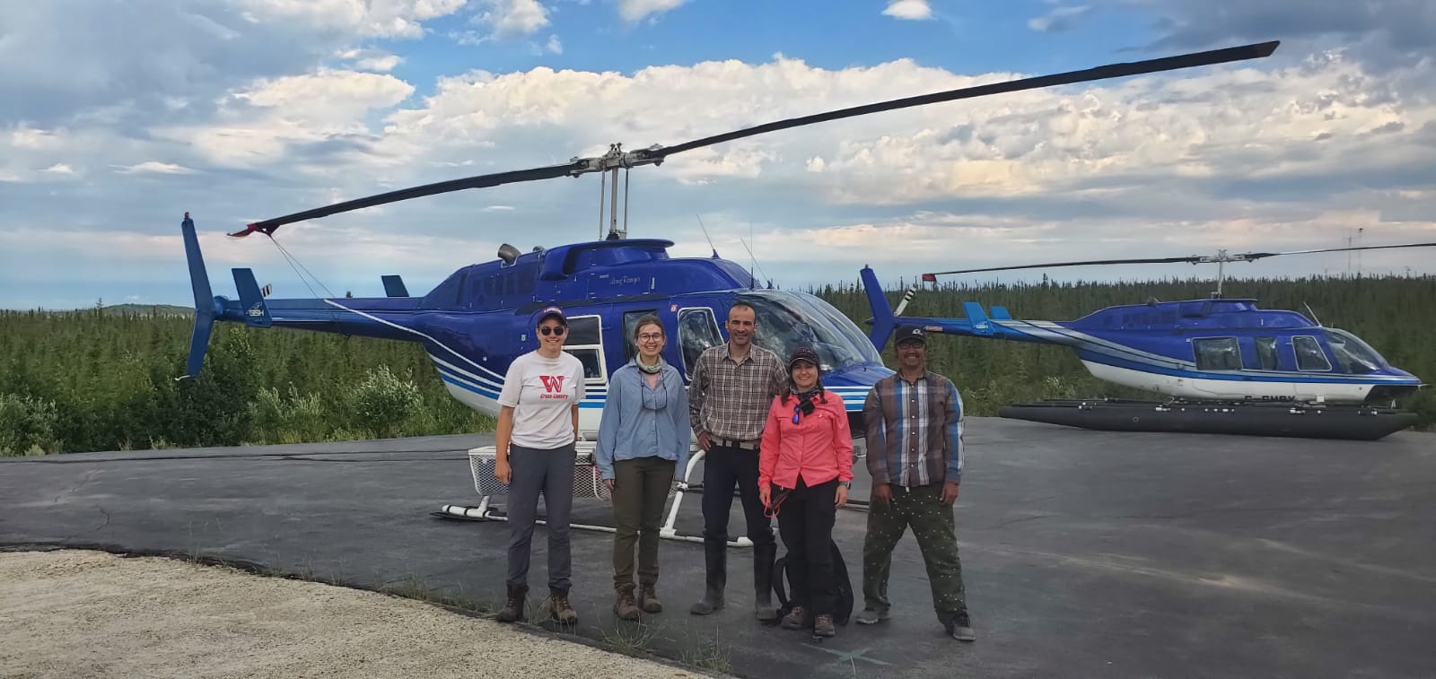 5 people stand in front of a helicopter